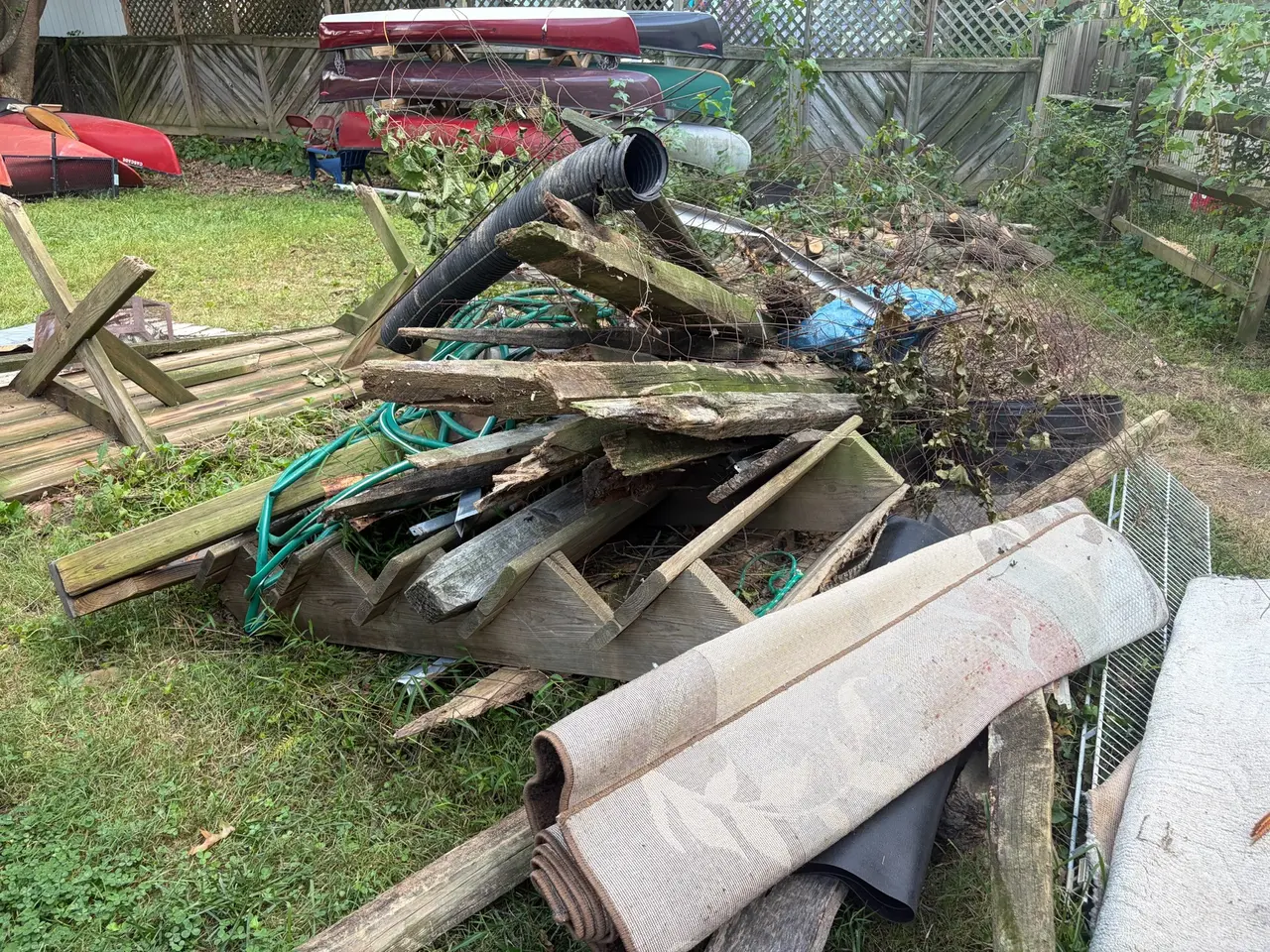 Old boards, dismantled wood sections and other debris piled in front of a canoe rack.